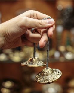 person holding gold steel round ornament