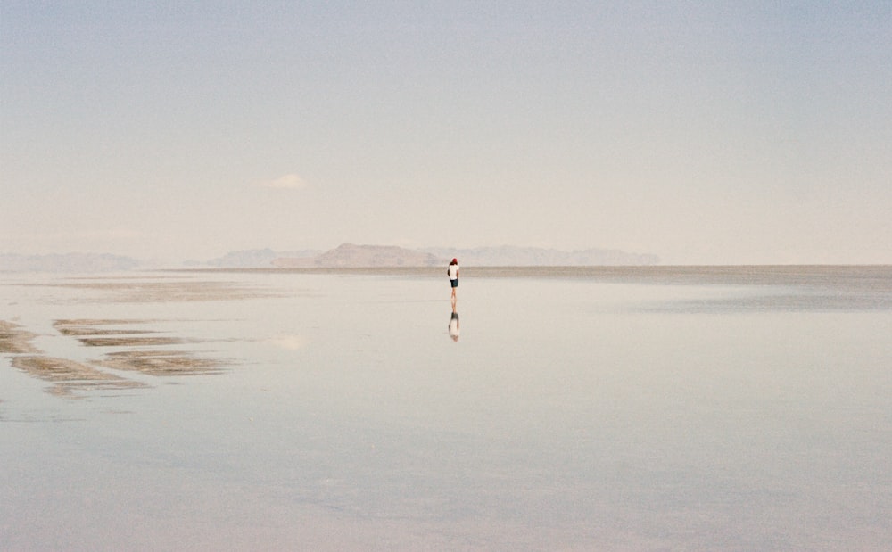 person in white shirt walking on beach during daytime