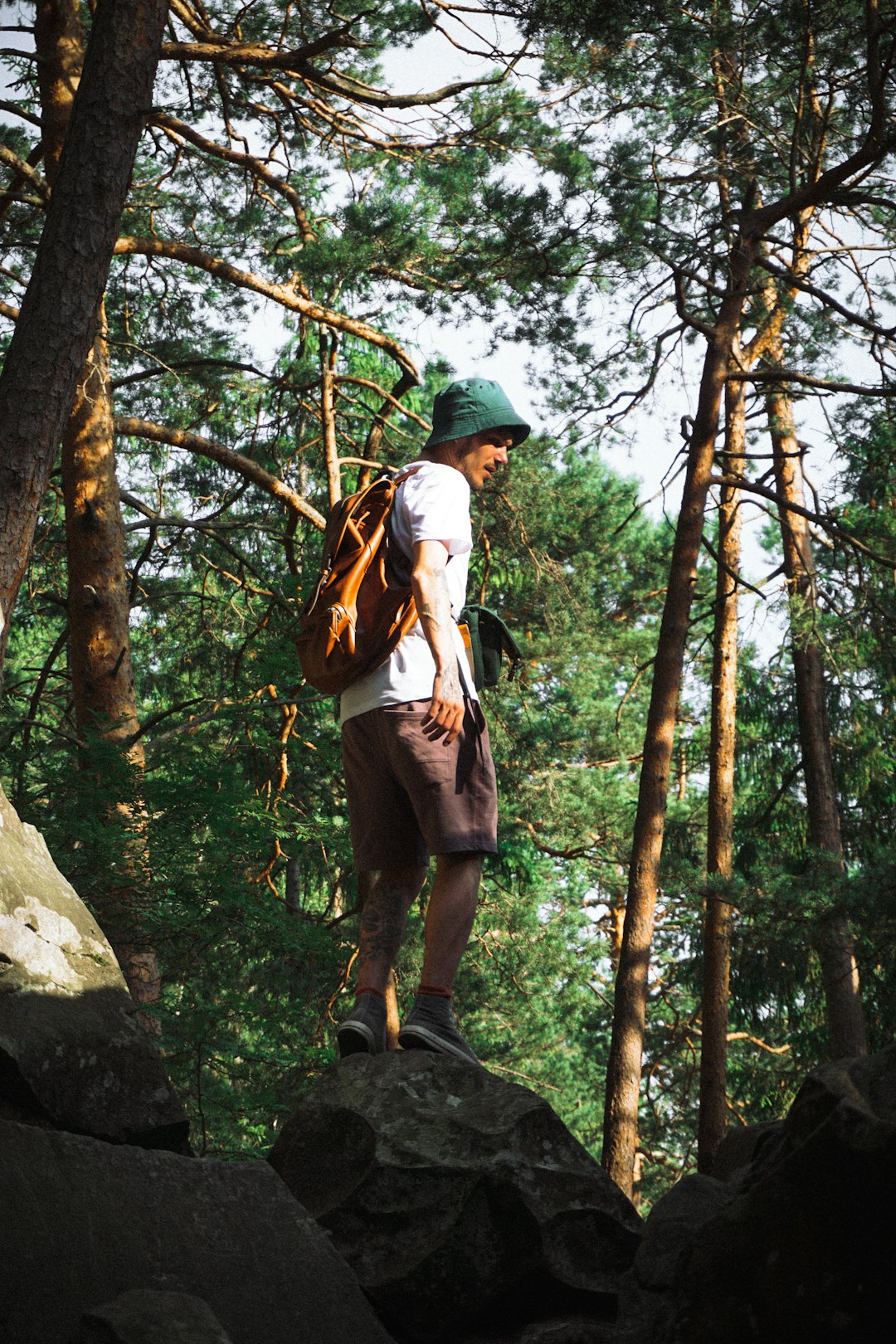 man in white shirt and brown pants standing on brown rock