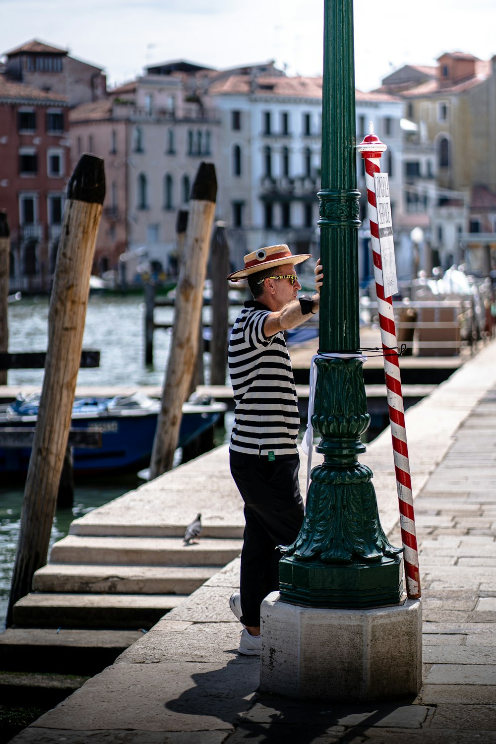 person in black and white striped long sleeve shirt and black pants sitting on wooden dock