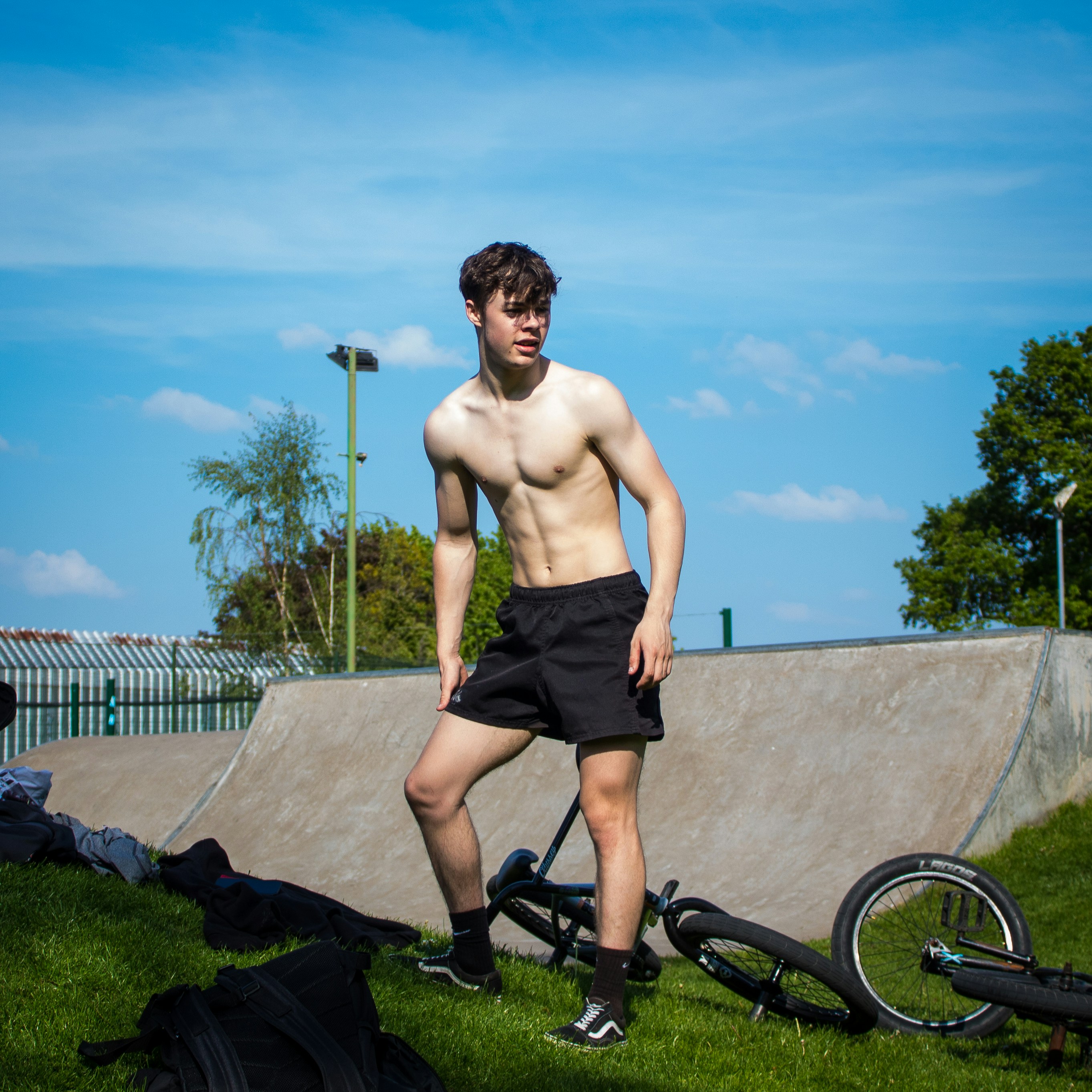 topless man in black shorts standing on gray concrete pavement during daytime