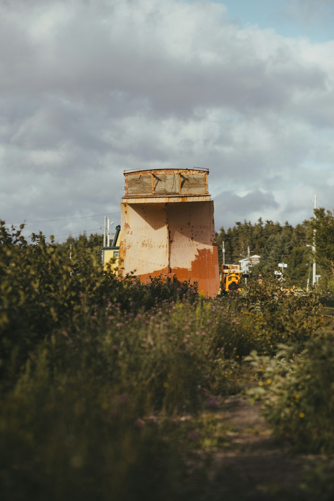 brown concrete building surrounded by green trees under white clouds during daytime