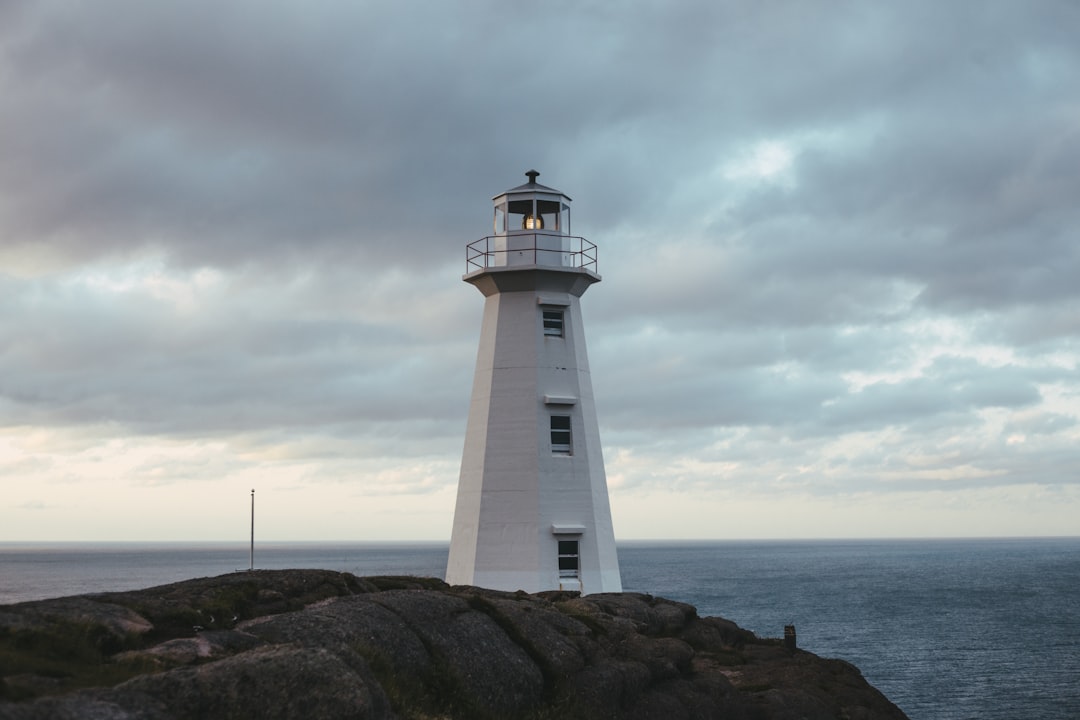 white and black lighthouse near body of water during daytime