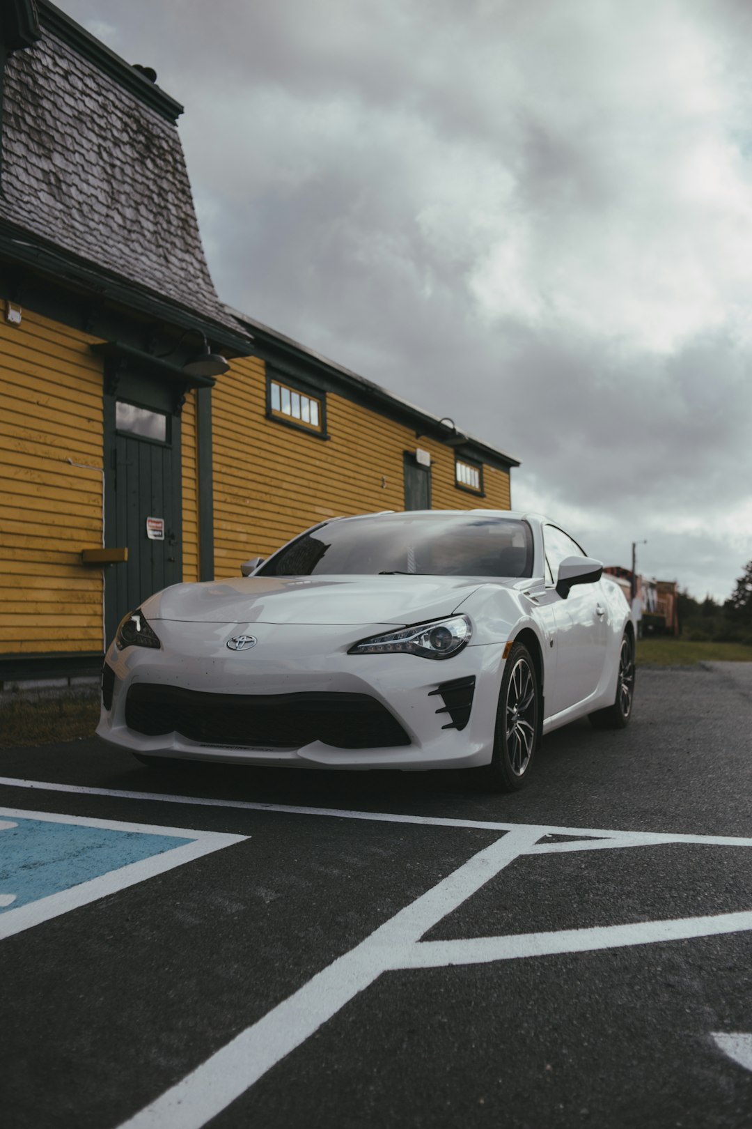 white porsche 911 parked near brown wooden house under white clouds during daytime