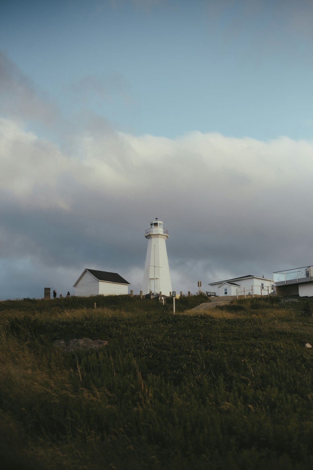 white lighthouse on green grass field under white clouds during daytime