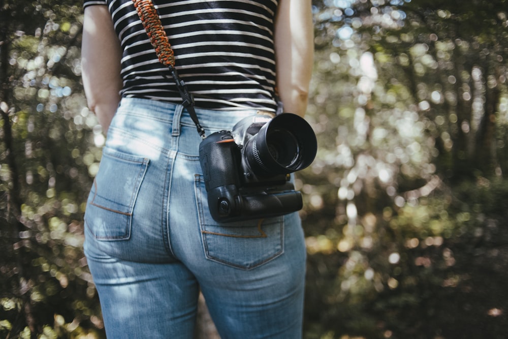Woman in black and white stripe shirt and blue denim jeans holding black  dslr camera photo – Free Grey Image on Unsplash