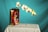 A still life setup featuring a metal fuel canister labeled 'TRUFUEL' with a 50:1 mix ratio, placed on a white cloth-covered table. A delicate branch of white orchids with purple centers stretches outwards from the canister against a solid turquoise background.