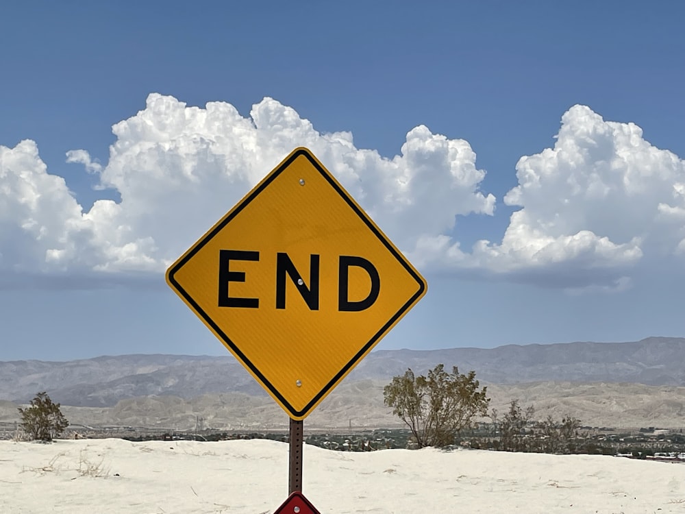 yellow and black road sign under white clouds and blue sky during daytime