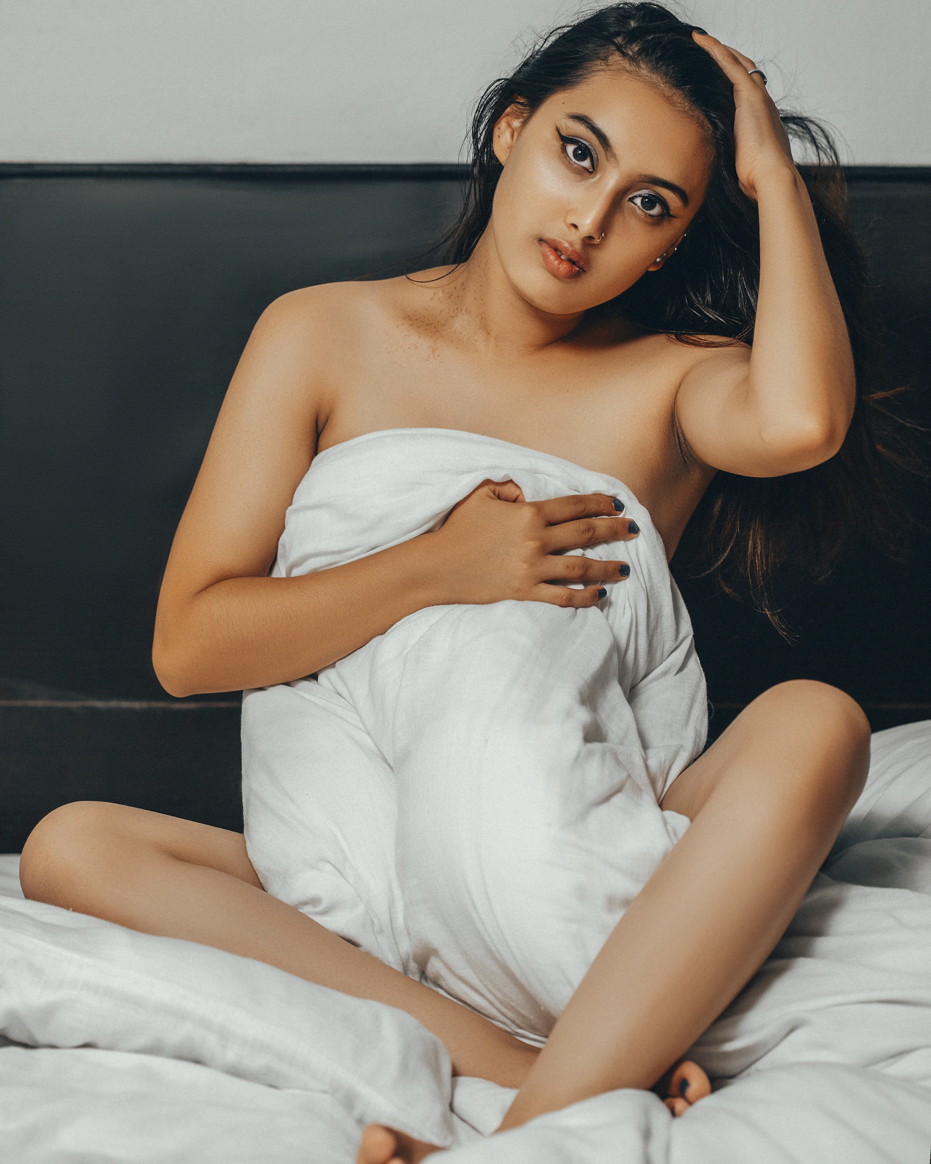 woman in white tube dress lying on black leather couch