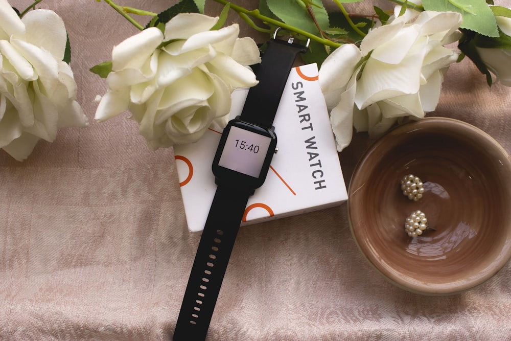 black smart watch on white flower