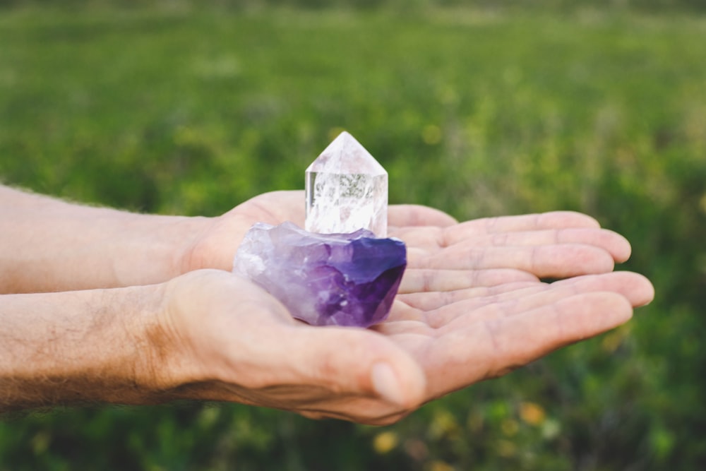 person holding purple and white glass pyramid