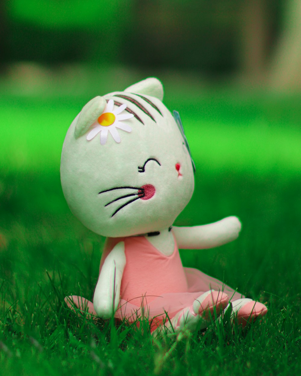 푸른 잔디에 흰색과 분홍색 고양이 봉제 장난감