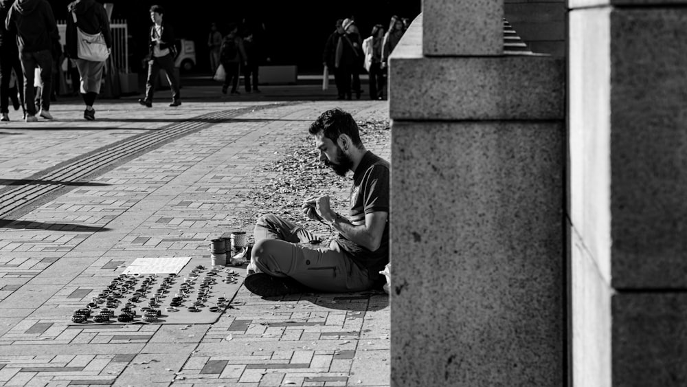 hombre en camisa de manga larga en blanco y negro sentado en un banco de hormigón