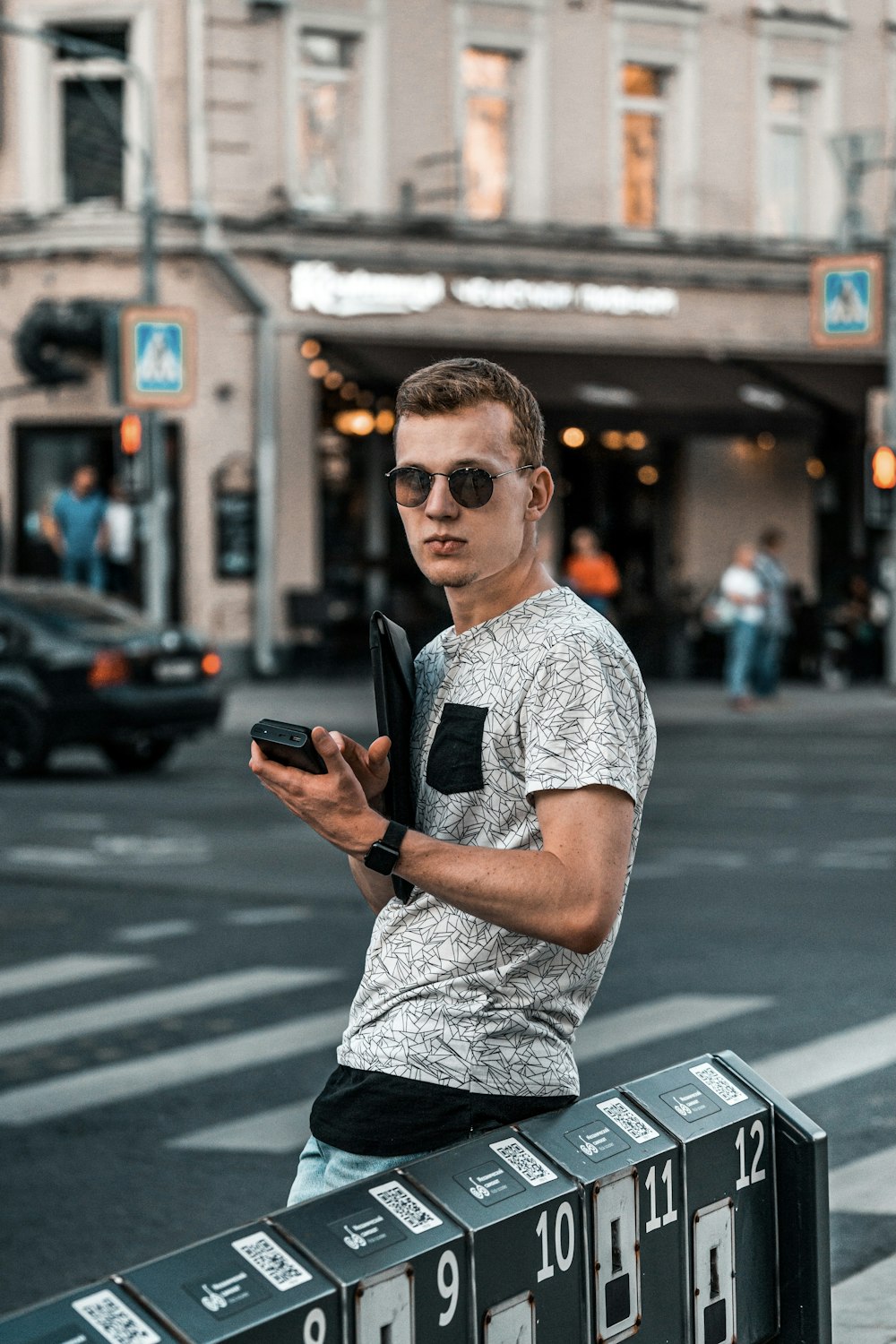 Mann in weiß-schwarzem Rundhals-T-Shirt mit schwarzer Sonnenbrille auf dem Bürgersteig während