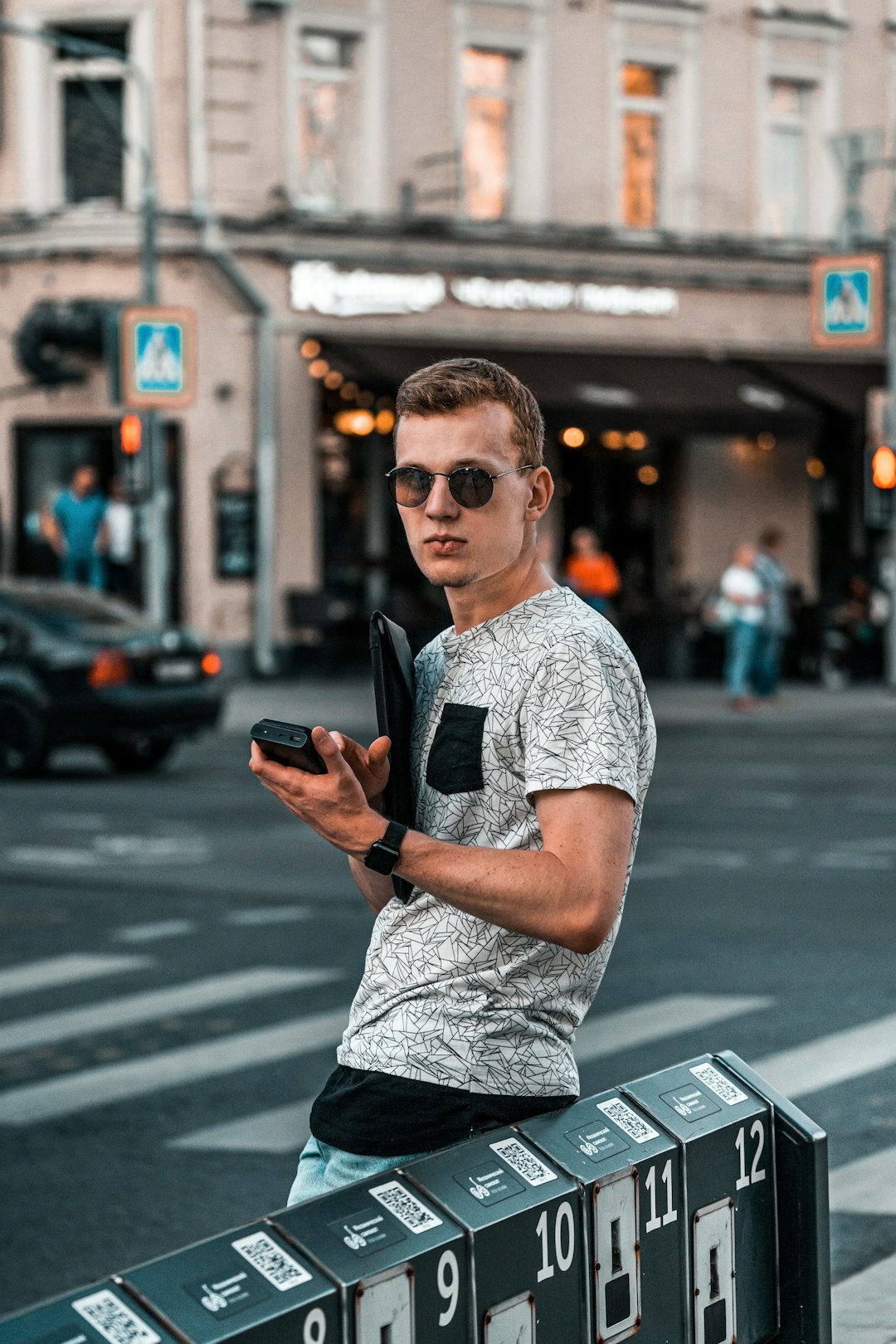 man in white and black crew neck t-shirt wearing black sunglasses standing on sidewalk during