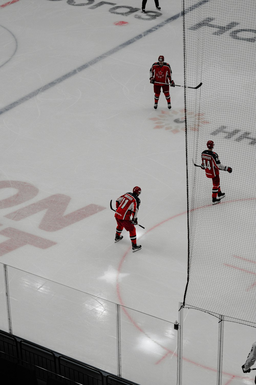 man in red jersey shirt and black pants playing ice hockey