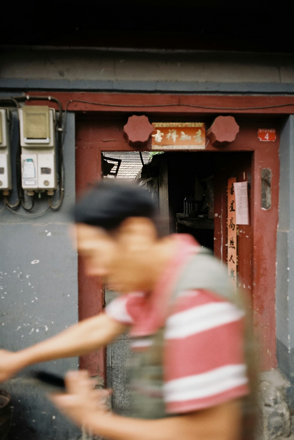 man in red and white stripe polo shirt standing near red wooden door