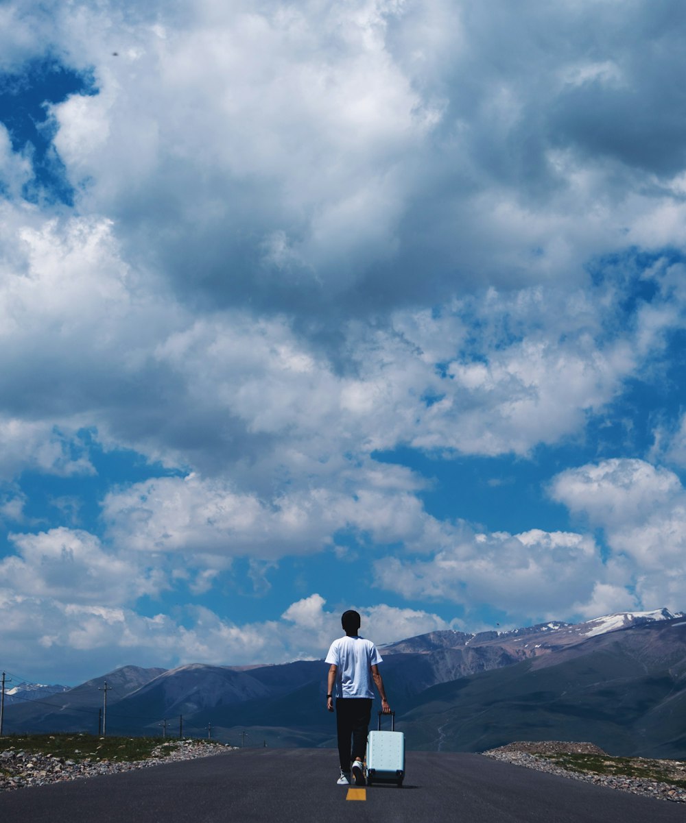 man in white shirt standing on top of mountain under cloudy sky during daytime