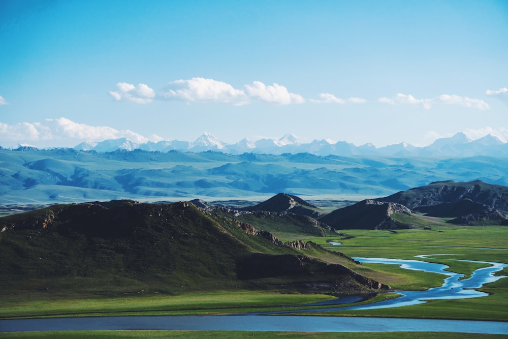 green grass field near body of water under blue sky during daytime