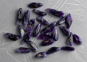 Hands gently holding a set of rune stones over an open book of runic meanings.