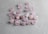 Several light pink crystals with engraved golden symbols are scattered on a textured gray surface. The stones have a polished finish, and the symbols seem to resemble ancient or mystical runes.