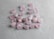 Several light pink crystals with engraved golden symbols are scattered on a textured gray surface. The stones have a polished finish, and the symbols seem to resemble ancient or mystical runes.