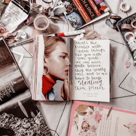 A vibrant collage of book covers, paintbrushes, and handwritten notes spread on a wooden table.