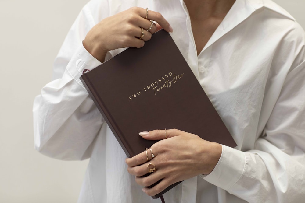 man in white dress shirt holding black book