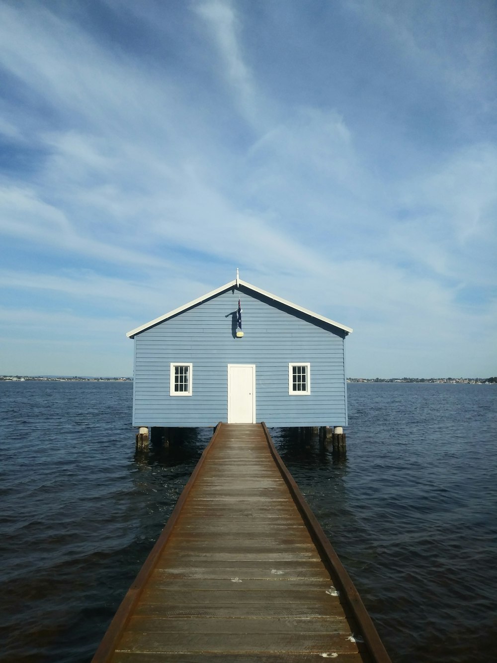 Maison en bois blanc et bleu sur la mer sous le ciel bleu pendant la journée