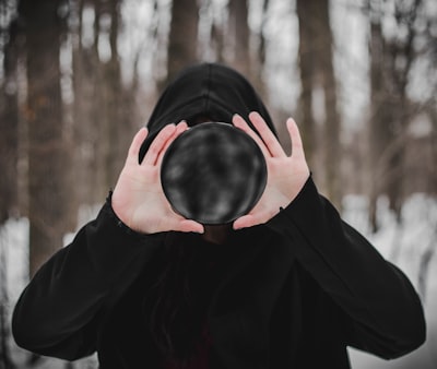 person in black long sleeve shirt covering face with black textile terrible teams background