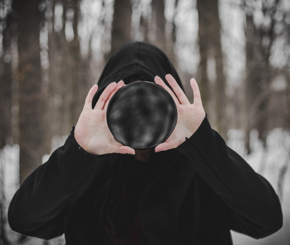 person in black long sleeve shirt covering face with black textile