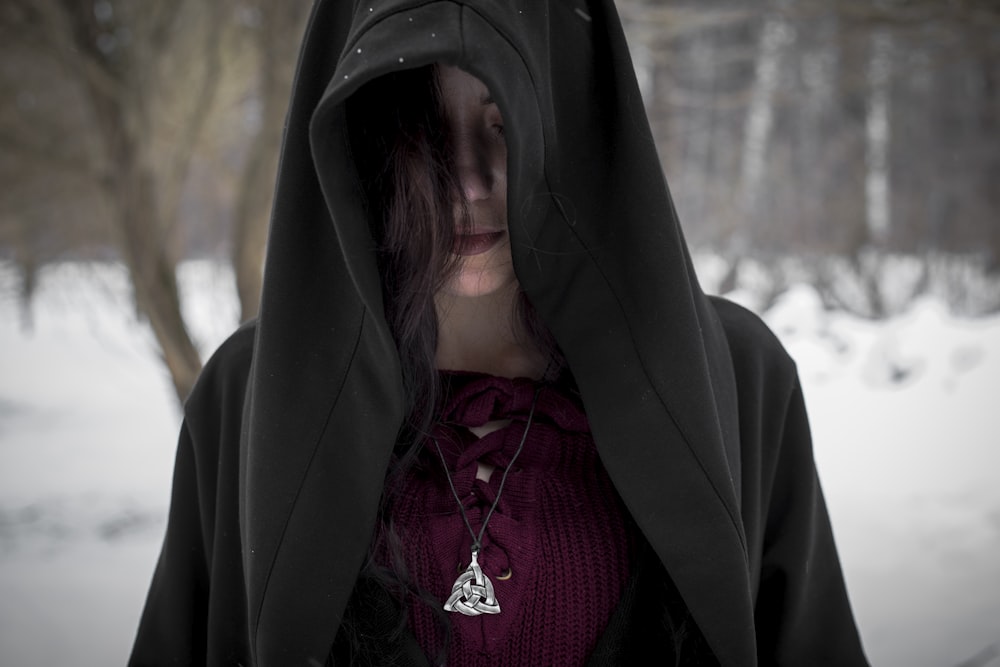 person in black hoodie standing on snow covered ground during daytime