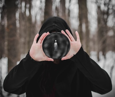 person in black hoodie covering face with black round ornament terrible zoom background