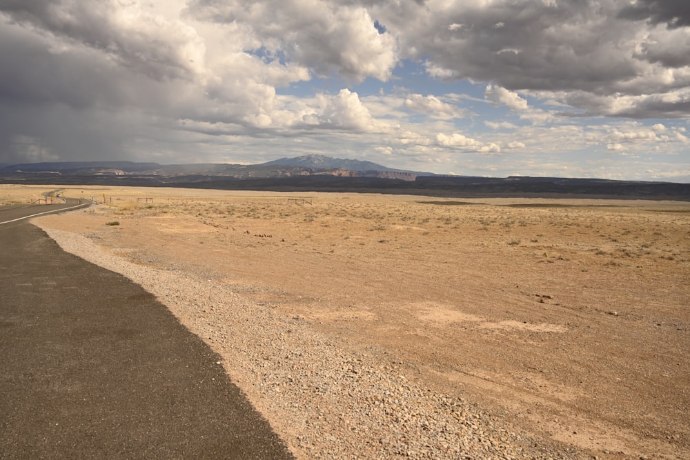 brown field under white clouds during daytime