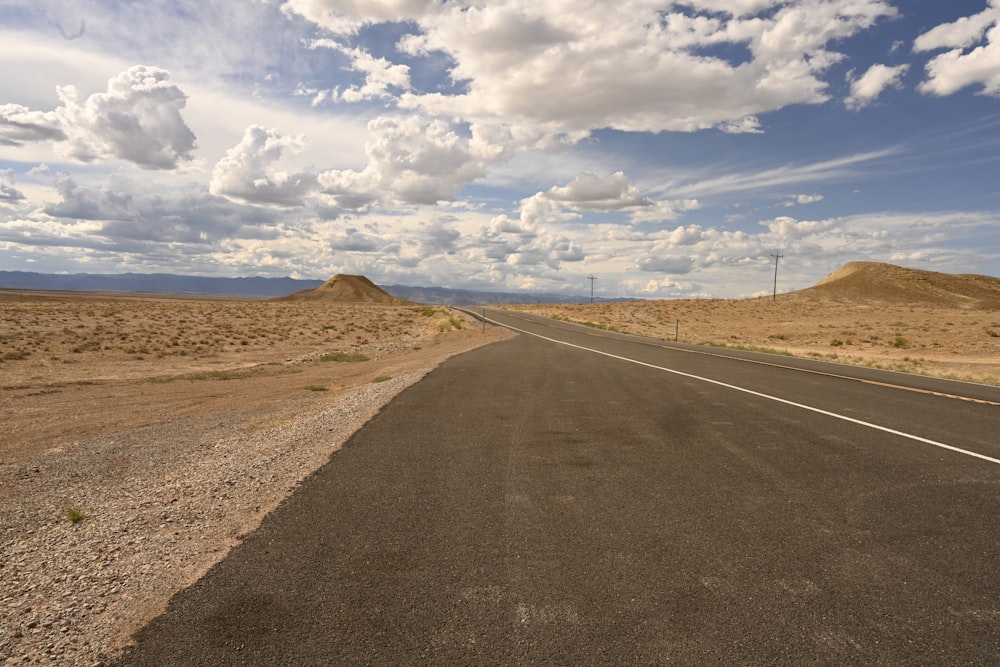 gray asphalt road under blue sky and white clouds during daytime