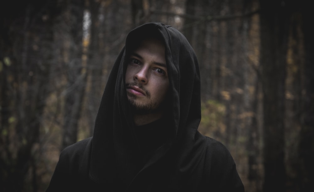 man in black hoodie standing near trees during daytime