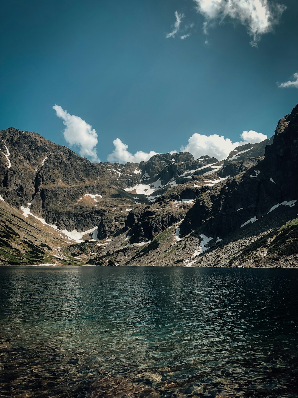 body of water near snow covered mountain during daytime