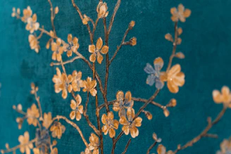 A close-up photo of traditional Indian motifs in deep teal and ivory, forming an elegant decorative border pattern.