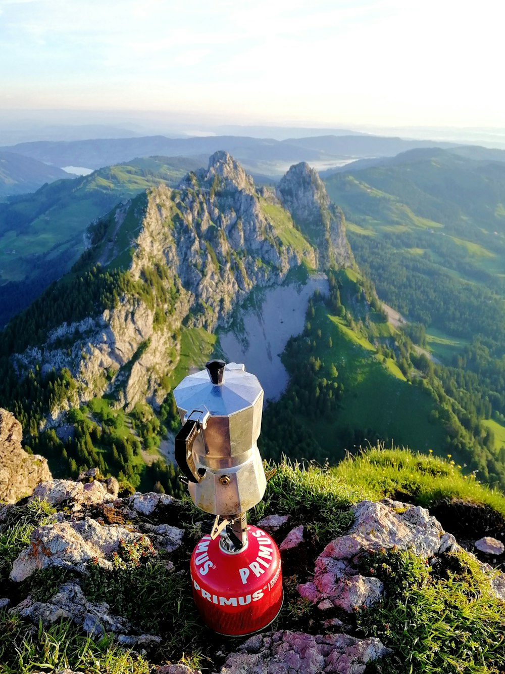 person in red shirt sitting on rock near green mountains during daytime