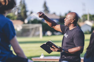 man in black crew neck t-shirt holding black tablet computer