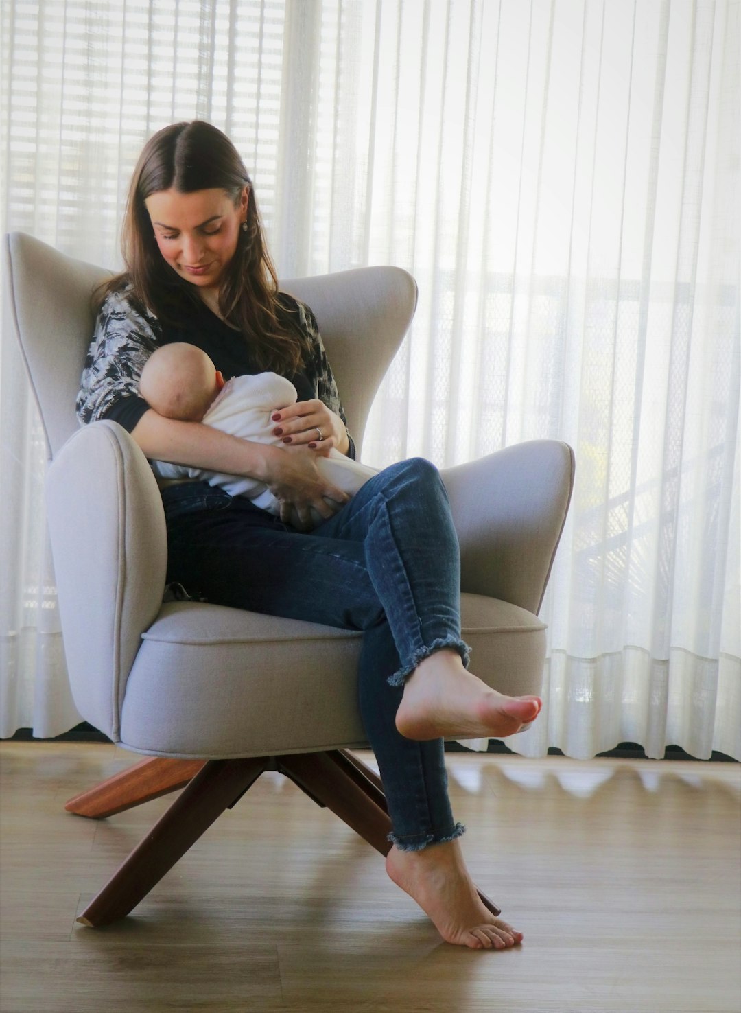 woman in black and white tank top and blue denim jeans sitting on white sofa chair