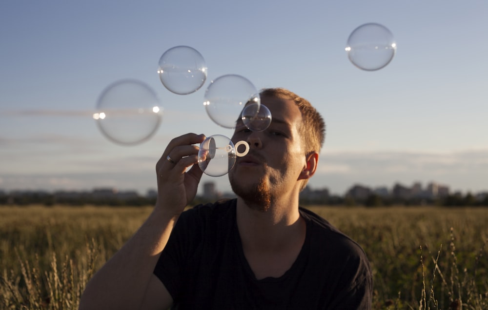 man in black crew neck shirt blowing bubbles