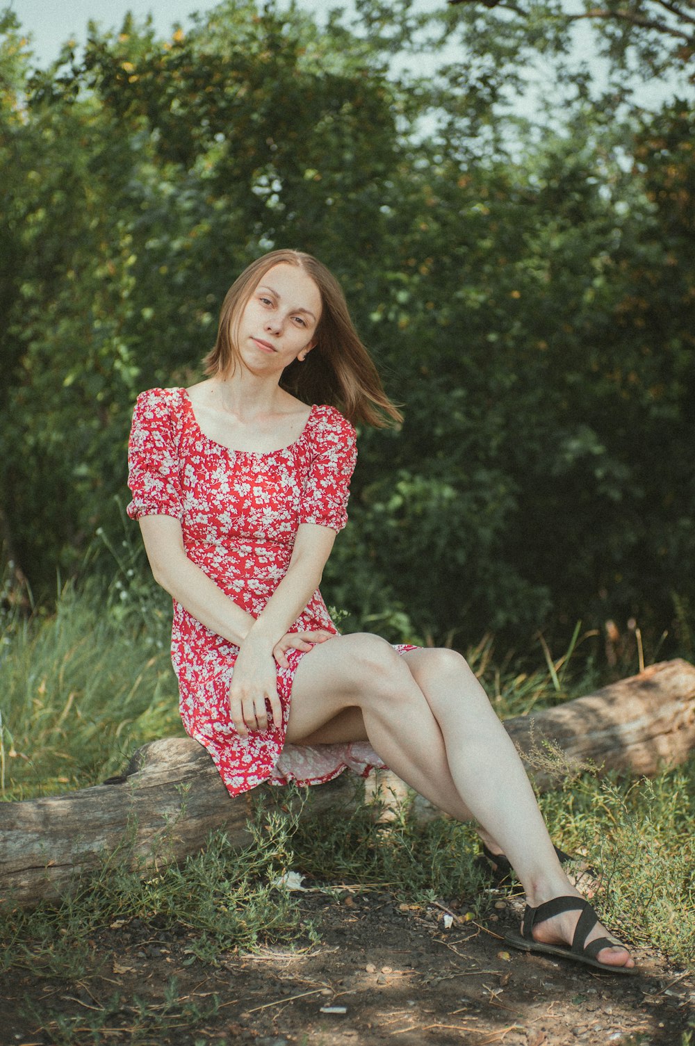 woman in red and white floral dress sitting on brown log