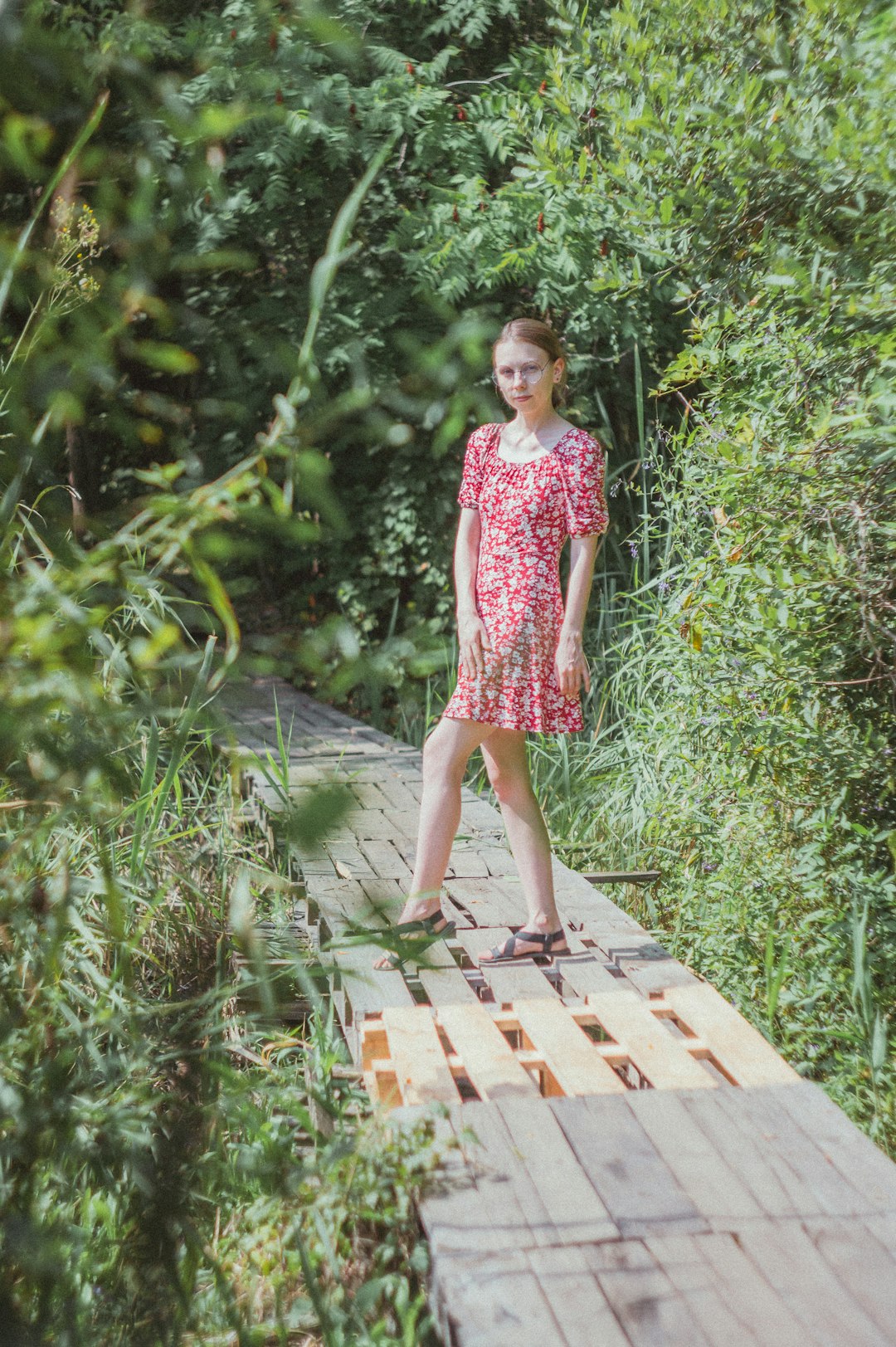 girl in pink and white floral dress standing on wooden pathway