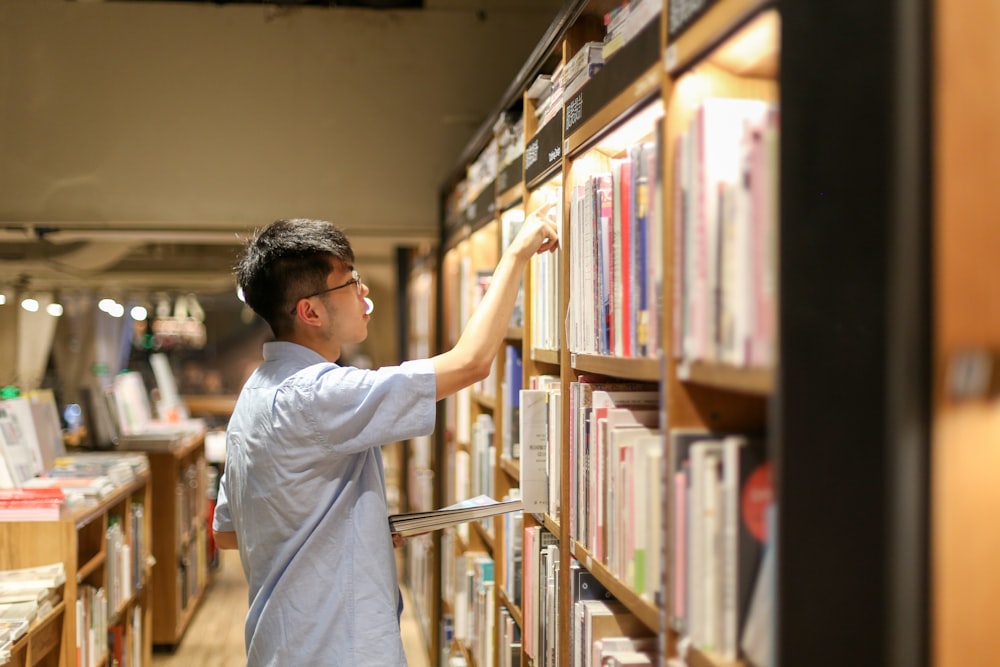 hombre con camiseta blanca de pie cerca de los libros