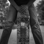 grayscale photo of person in black long sleeve shirt and black pants standing on concrete post