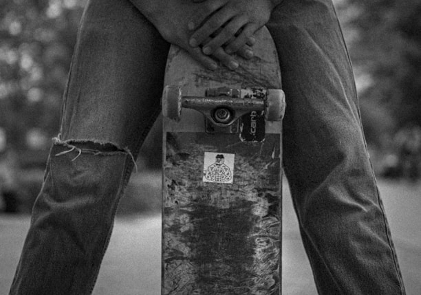 grayscale photo of person in black long sleeve shirt and black pants standing on concrete post