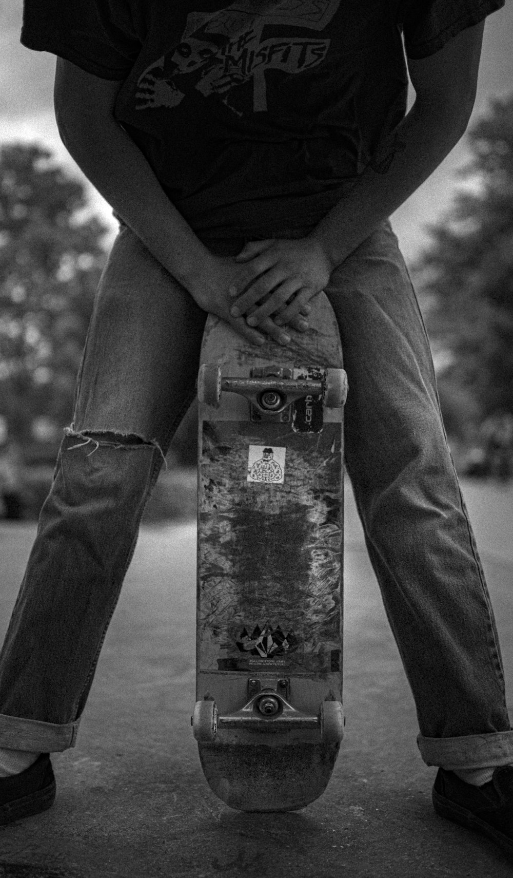 grayscale photo of person in black long sleeve shirt and black pants standing on concrete post