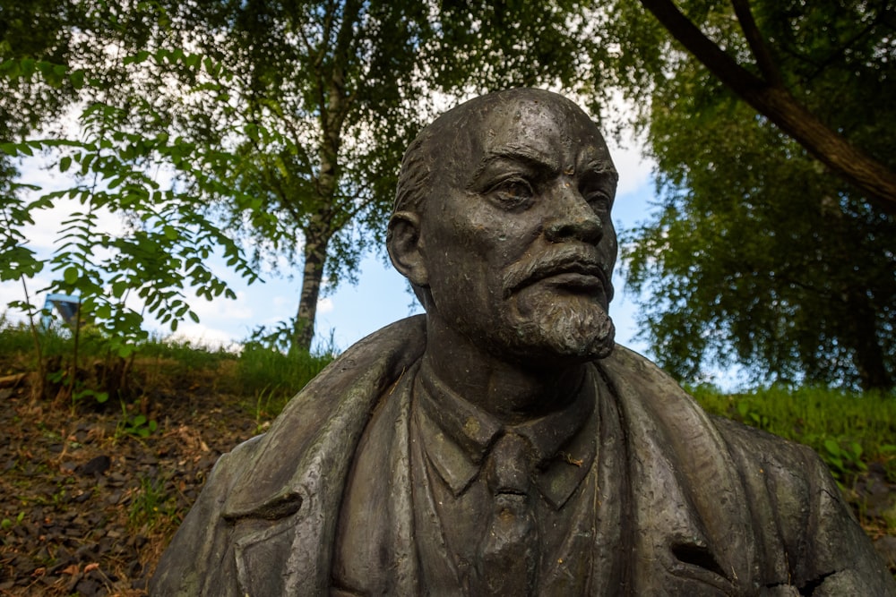 Statua di cemento grigio vicino agli alberi verdi durante il giorno