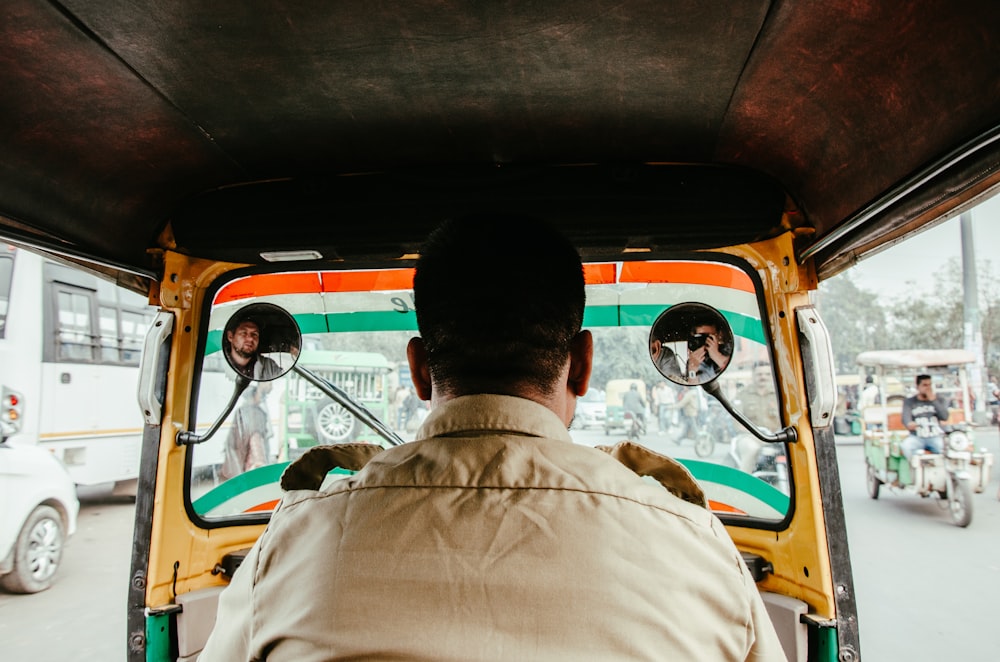 man in white button up shirt sitting inside orange bus during daytime